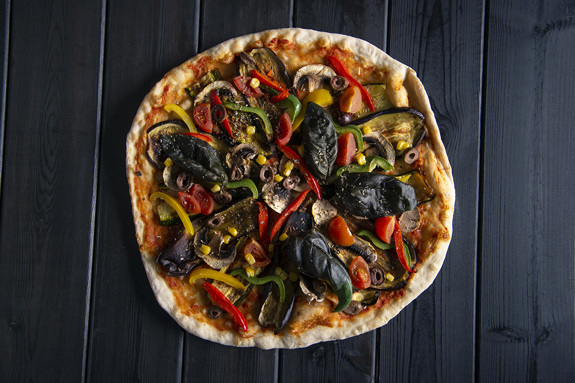 Pizza without cheese with eggplant, zucchini, mushroom, cherry tomatoes, colored peppers, olives, corn, basil and oregano